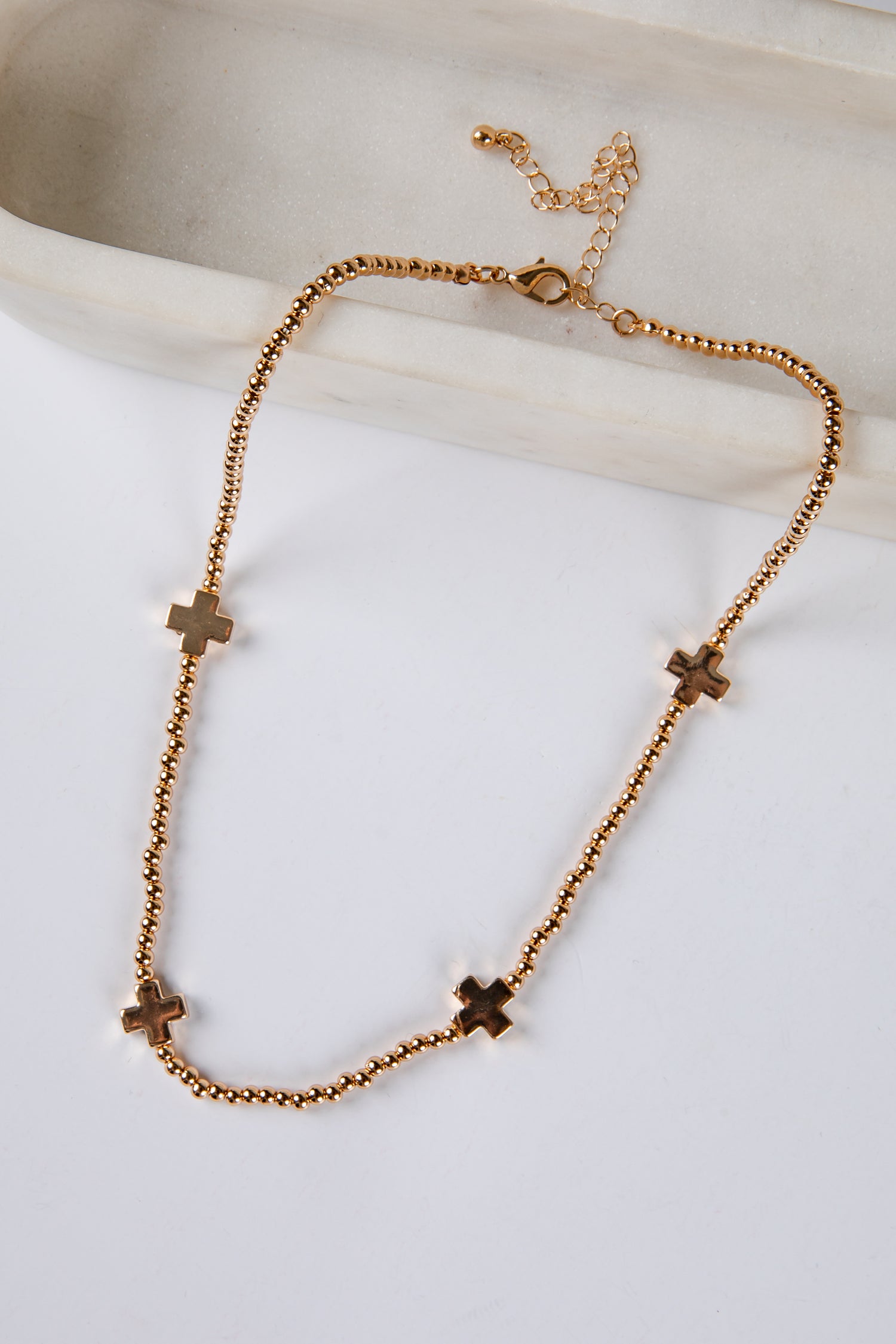 Gold necklace with cross pendants on a light background