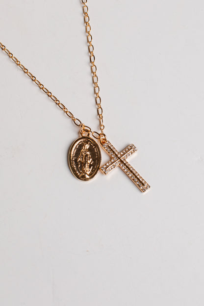 A rose gold chain necklace featuring two pendants: an oval Miraculous Medal pendant and a rectangular cross paved with small clear stones, displayed on a light gray background.