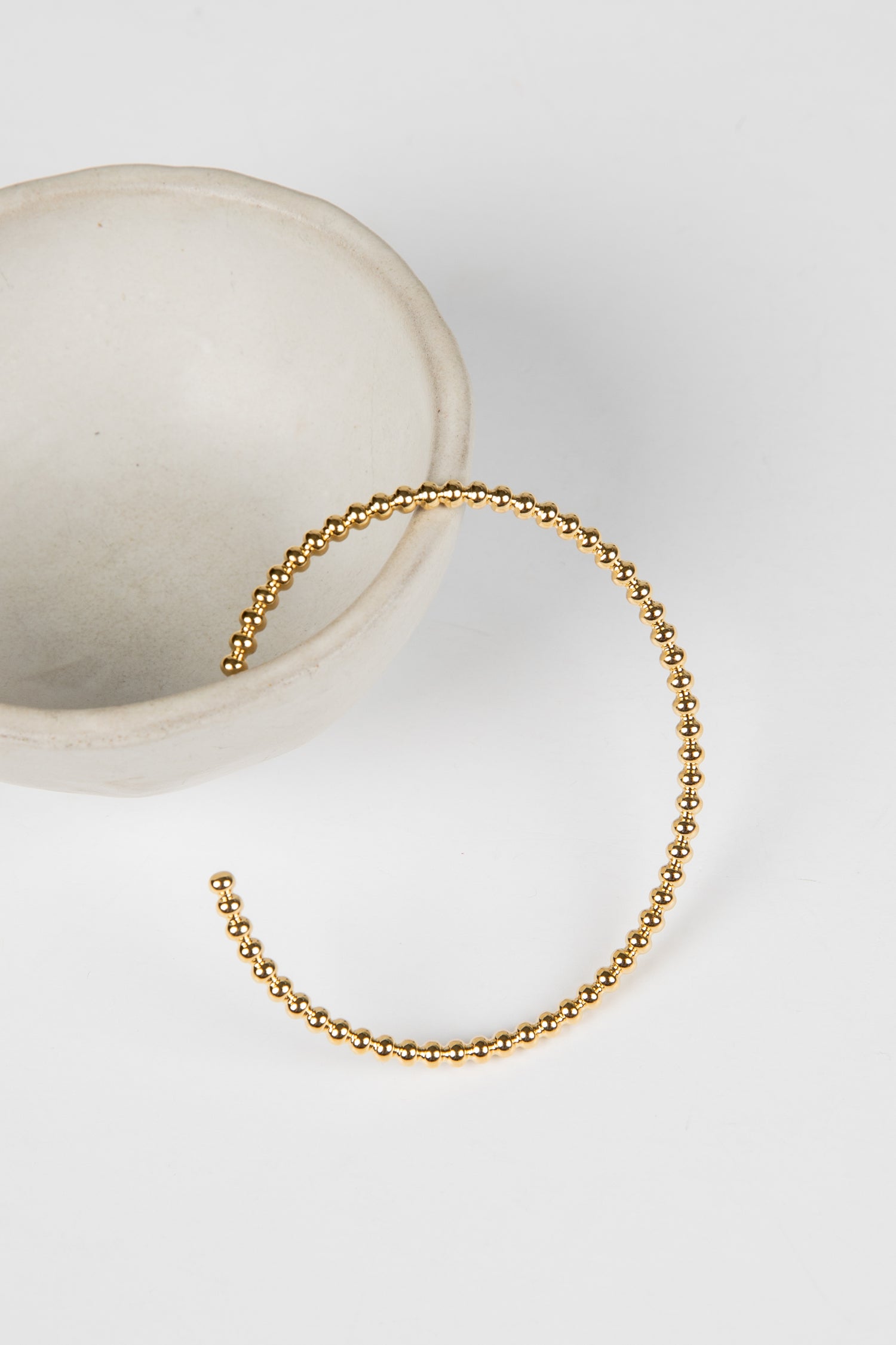 Gold beaded bracelet on a white surface
