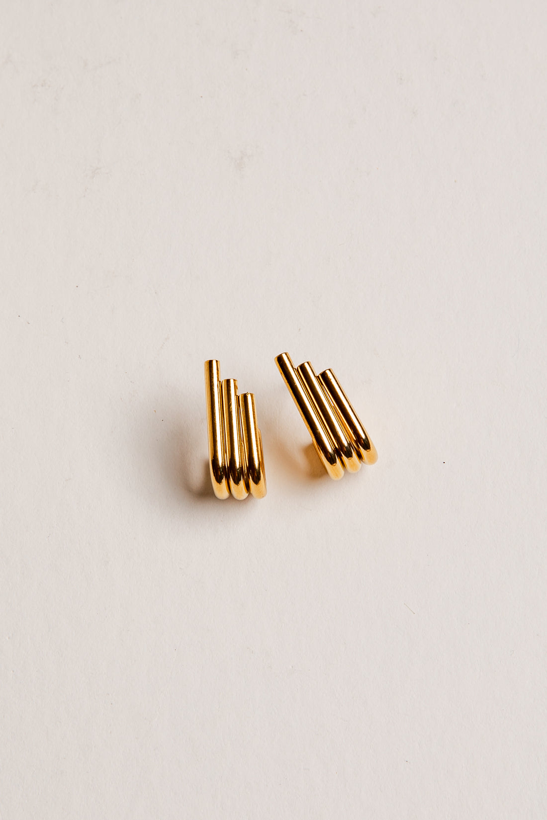 Gold earrings on a light beige background