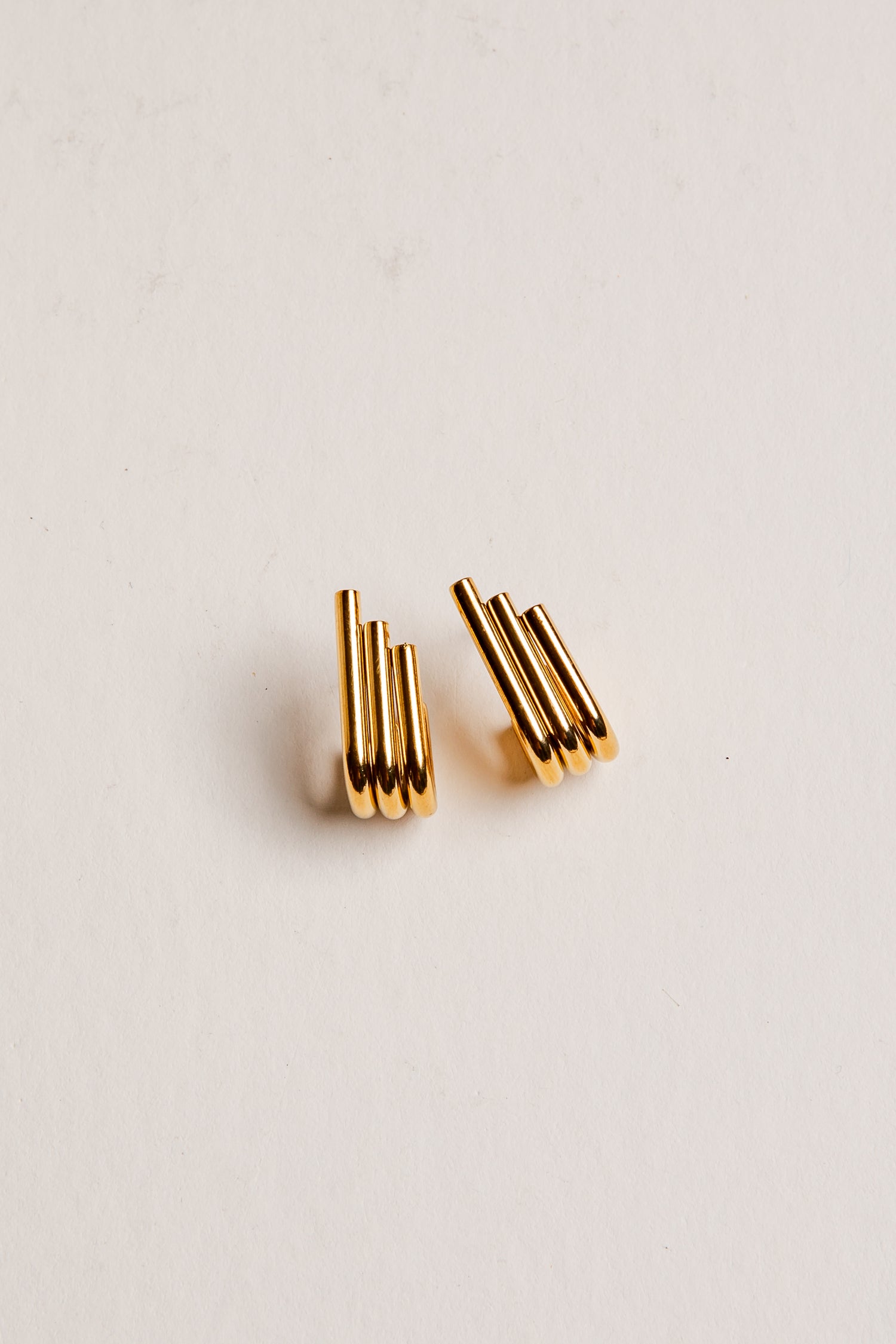 Gold earrings on a light beige background