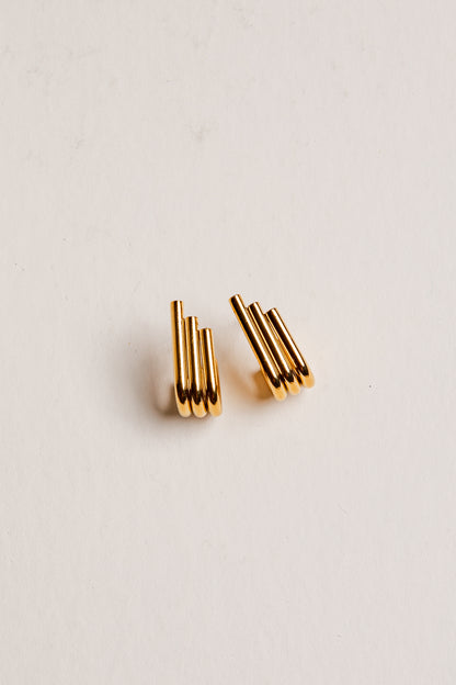 Gold earrings on a light beige background