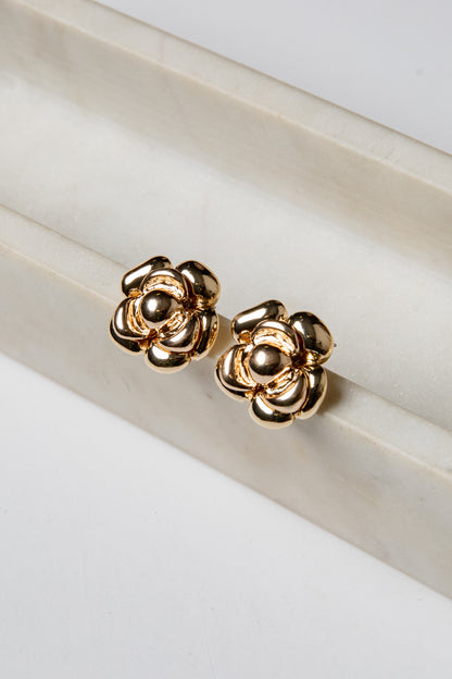 Gold flower-shaped earrings on a white surface