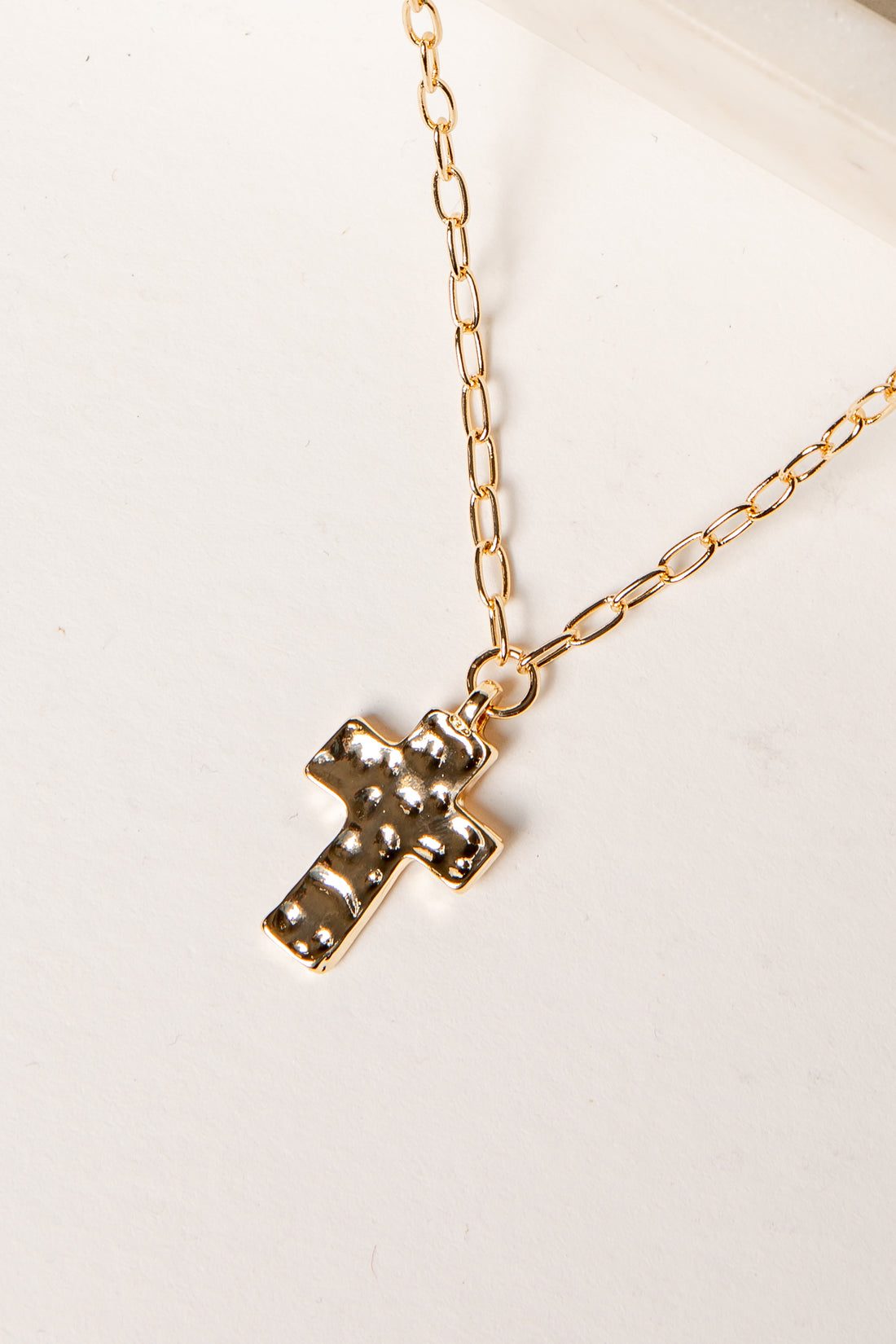 Gold cross necklace on a white background