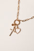 Gold necklace with cross and heart charms on a light background