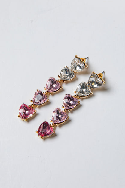 Pair of earrings with pink and clear gemstones on a light gray background