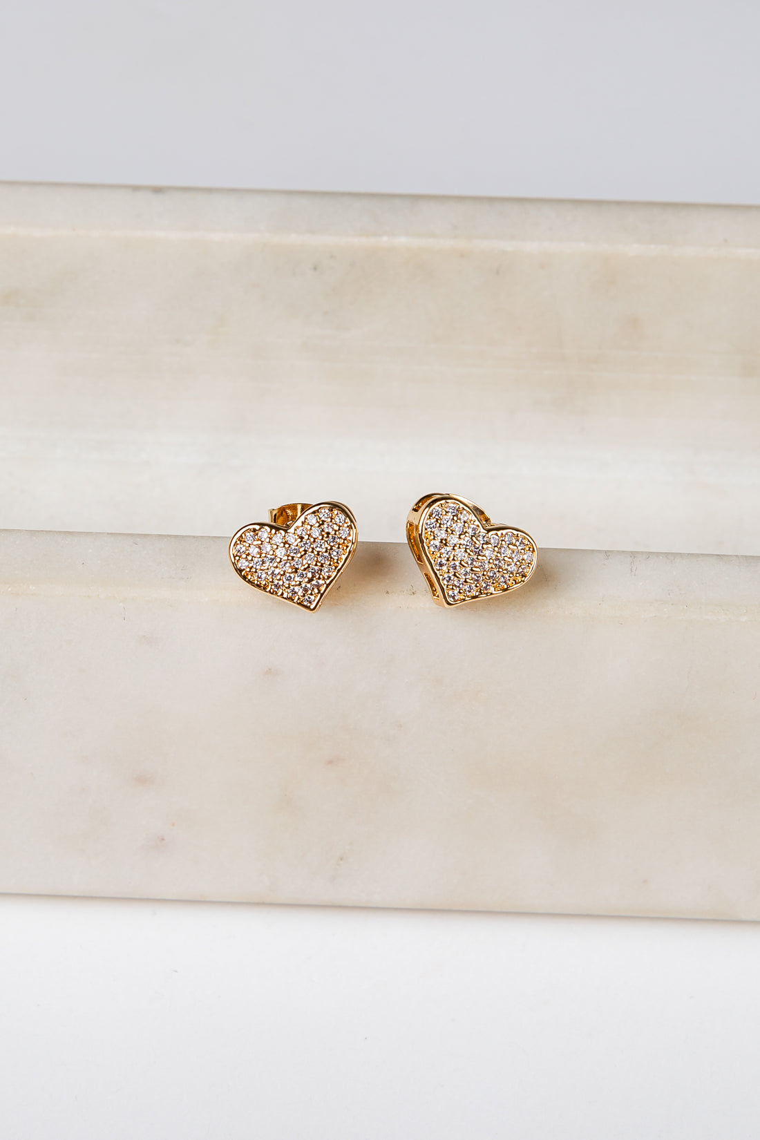 Heart-shaped gold earrings on a marble surface