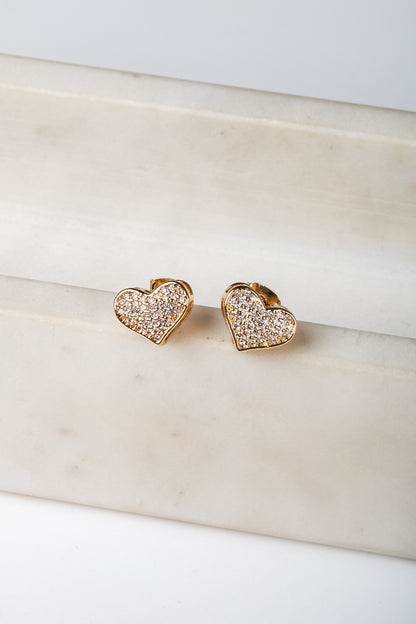 Heart-shaped earrings with embedded stones on a marble surface