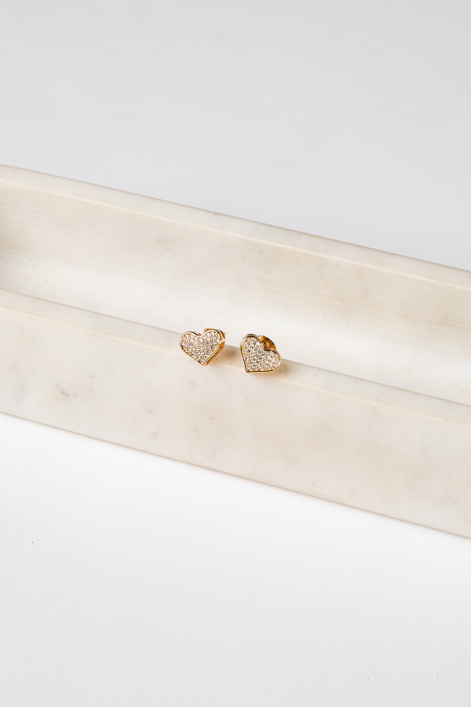 Gold heart-shaped earrings on a white satin ribbon