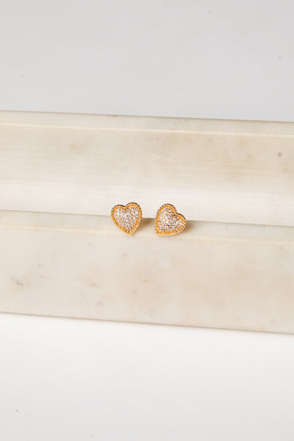 Heart-shaped earrings with clear stones on a light wooden surface