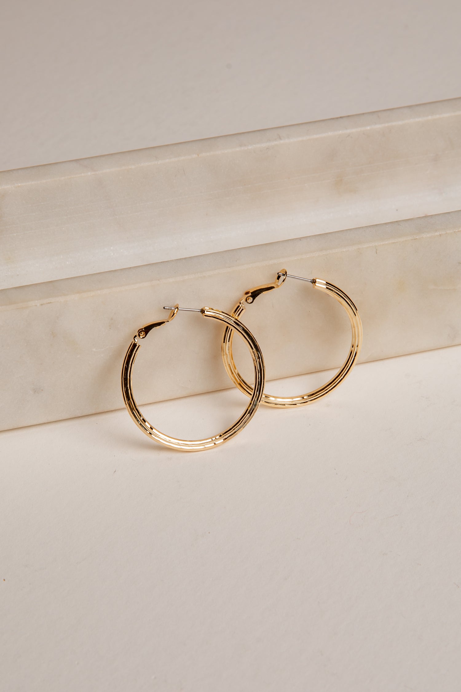 Gold hoop earrings on a light beige surface