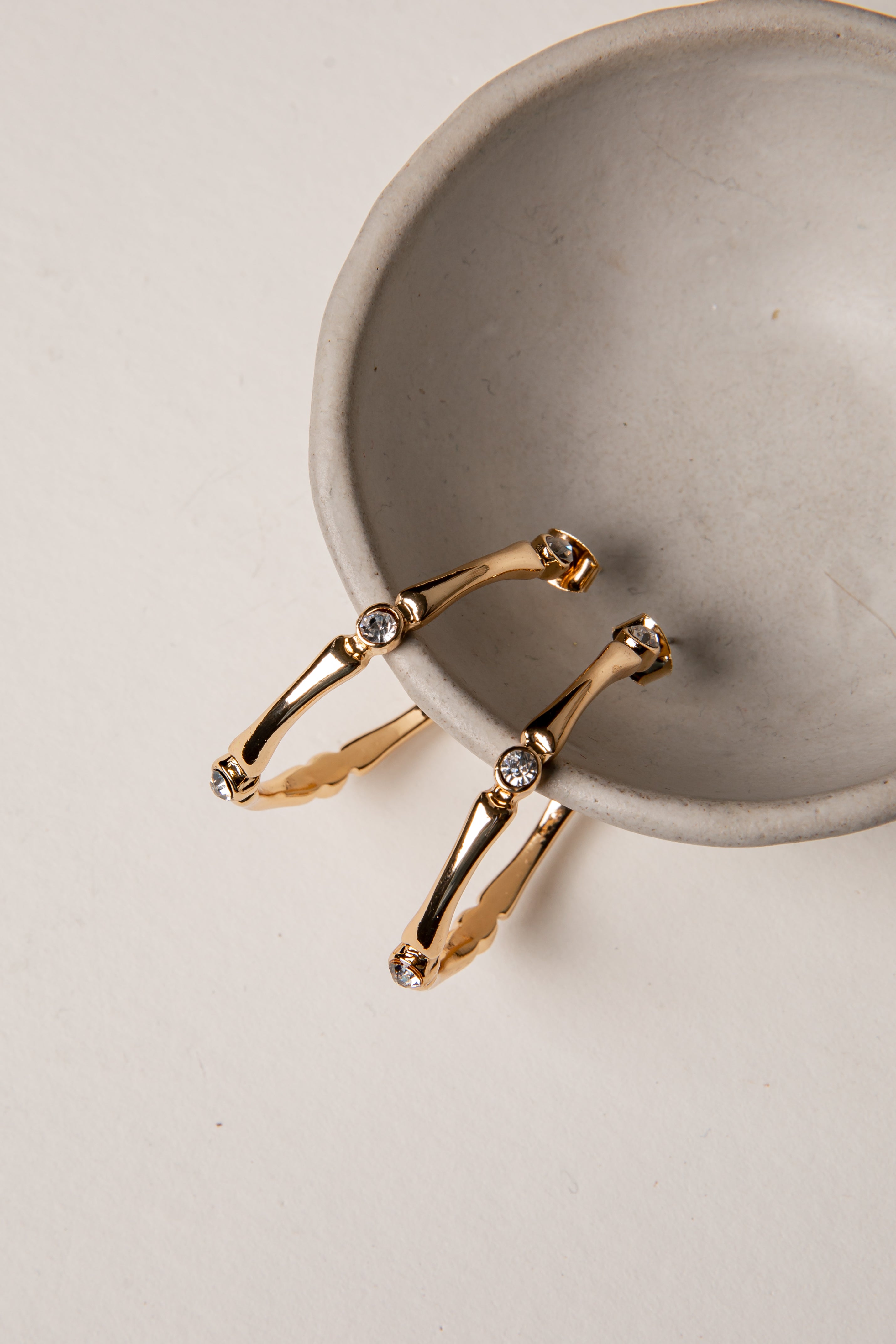 Gold bracelet with small stones on a gray ceramic dish