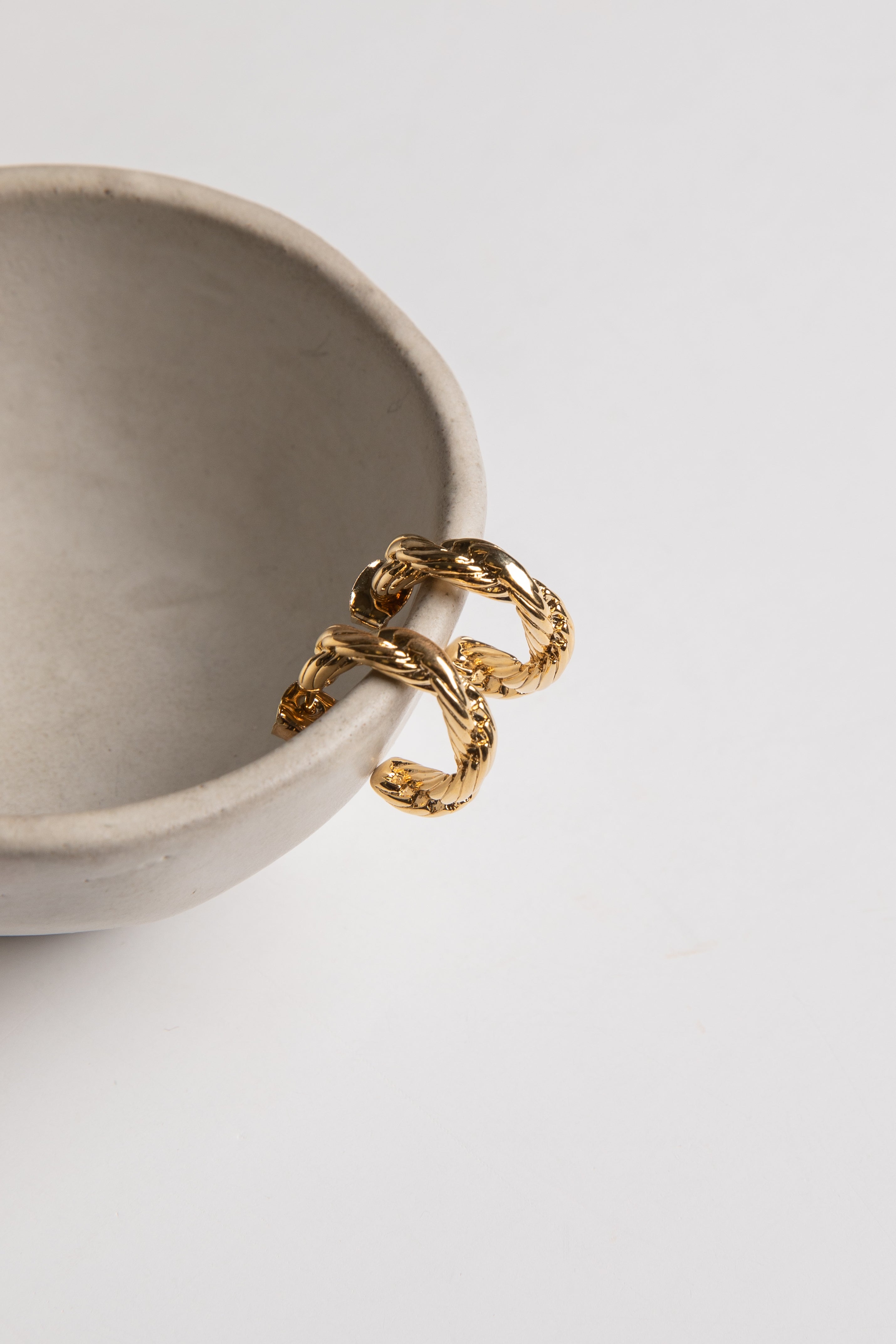 Gold ring on a beige ceramic bowl against a light gray background