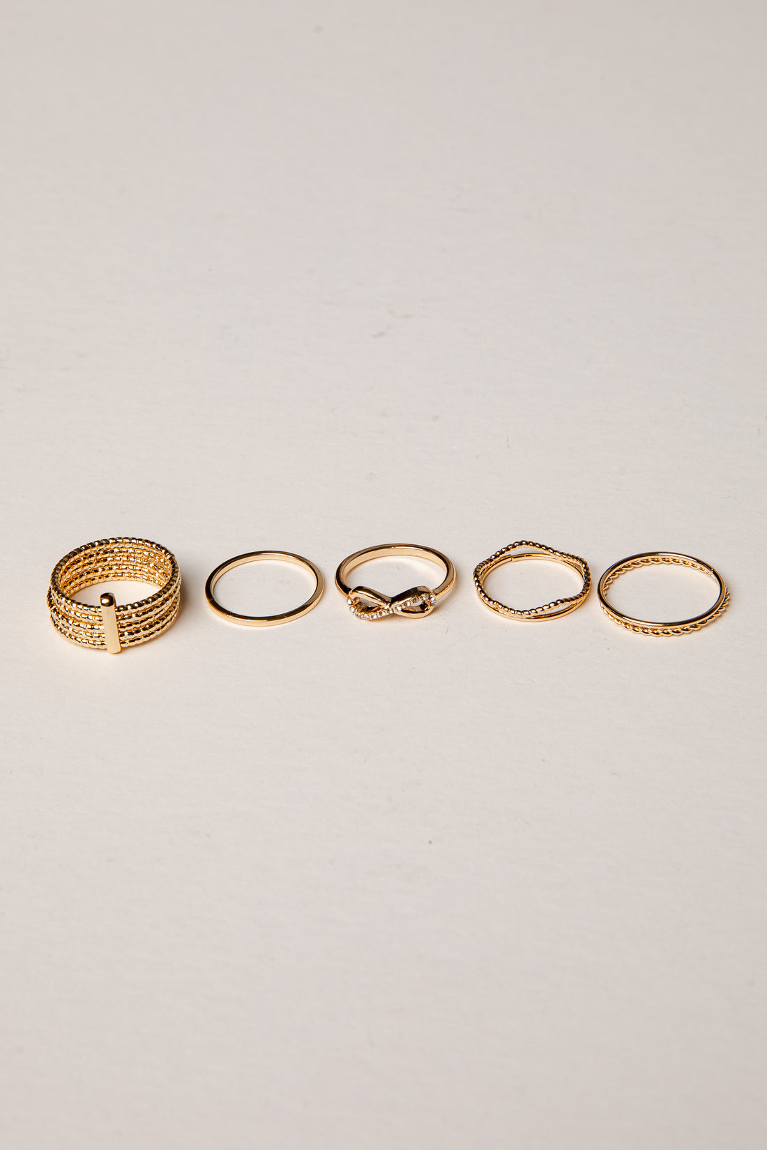 Set of five gold rings on a light gray background