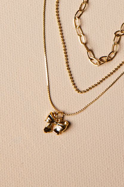 Three gold necklaces with different designs on a beige background