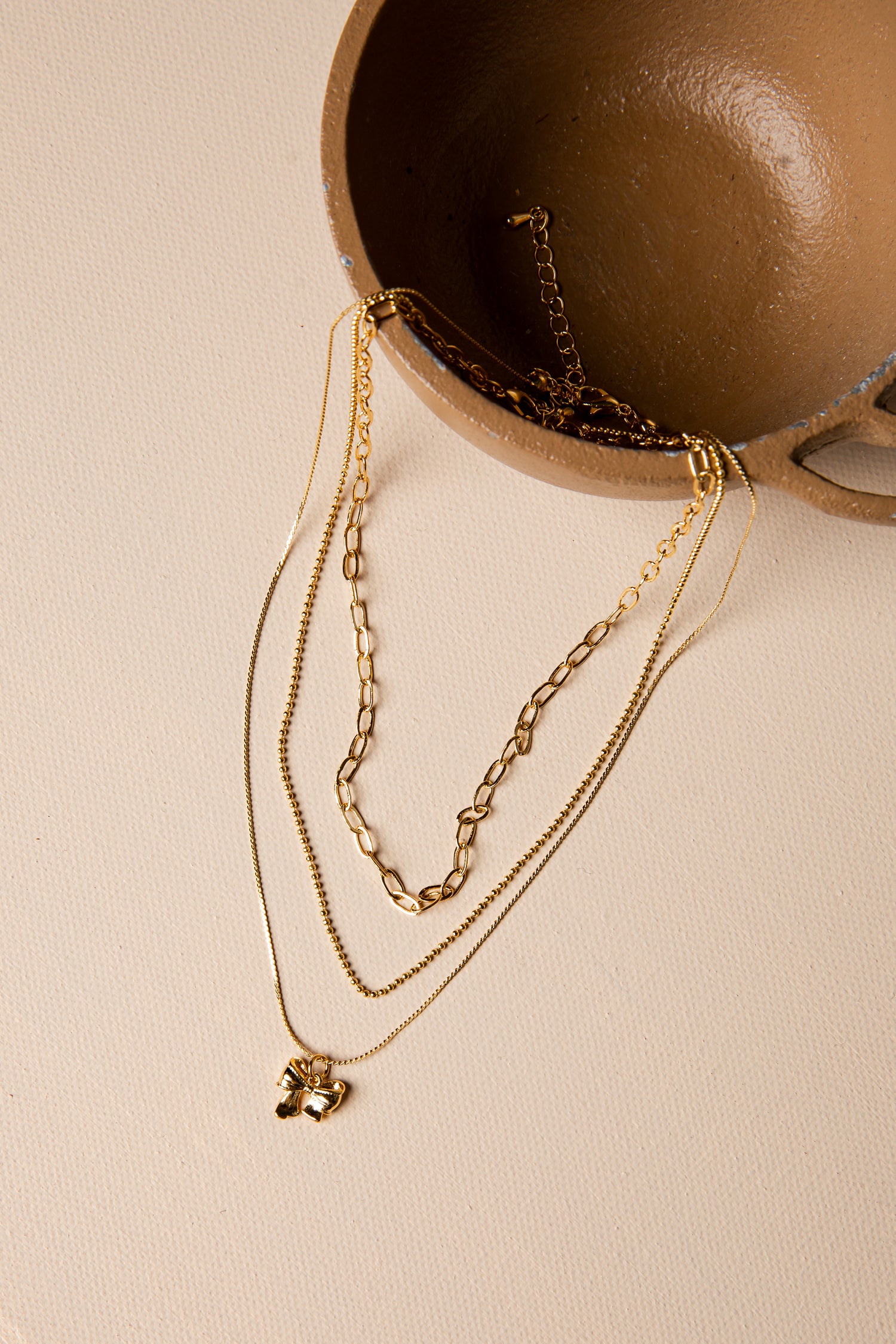 Gold necklaces with pendants on a beige surface