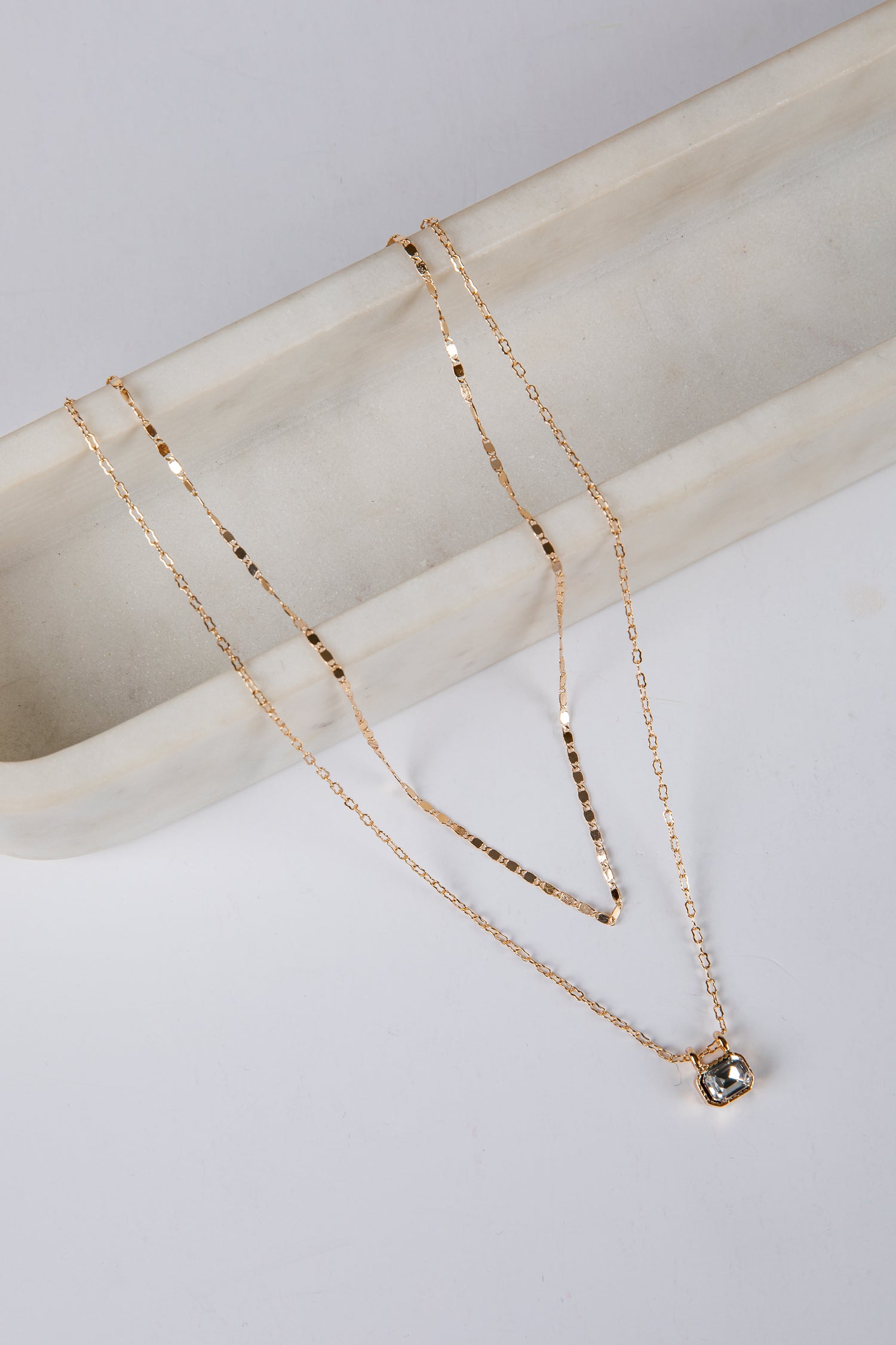 Gold necklace with a pendant on a marble surface