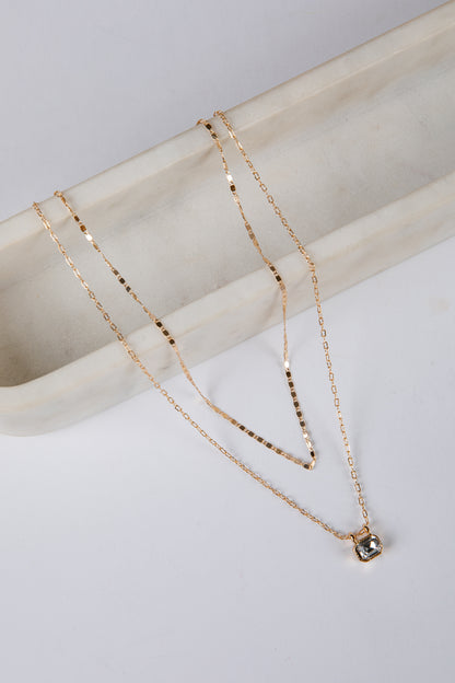 Gold necklace with a pendant on a marble surface
