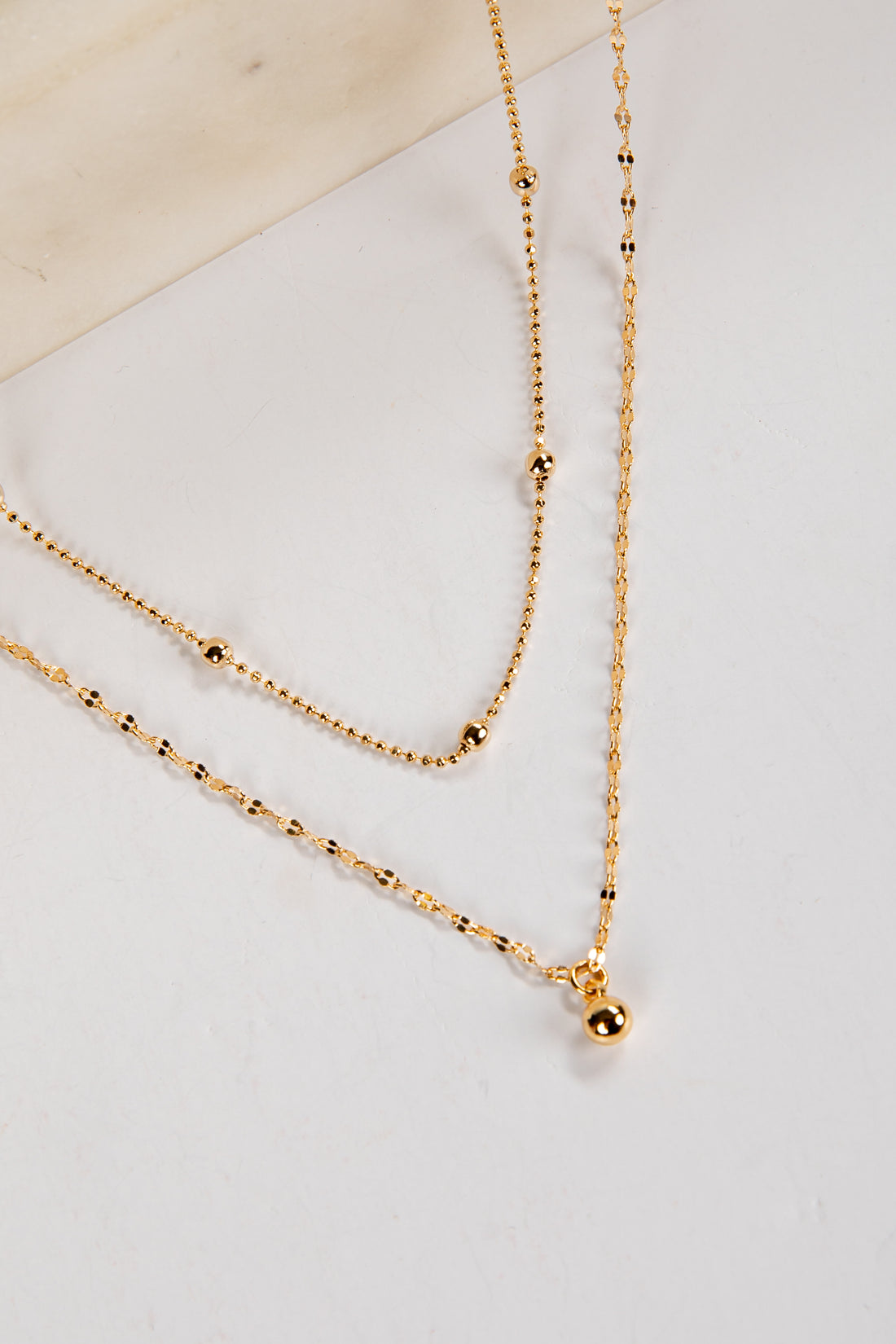 Gold necklace on a light gray surface