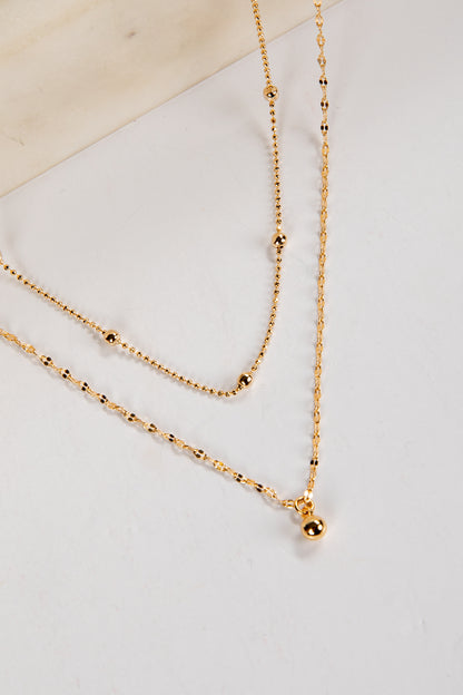 Gold necklace on a light gray surface