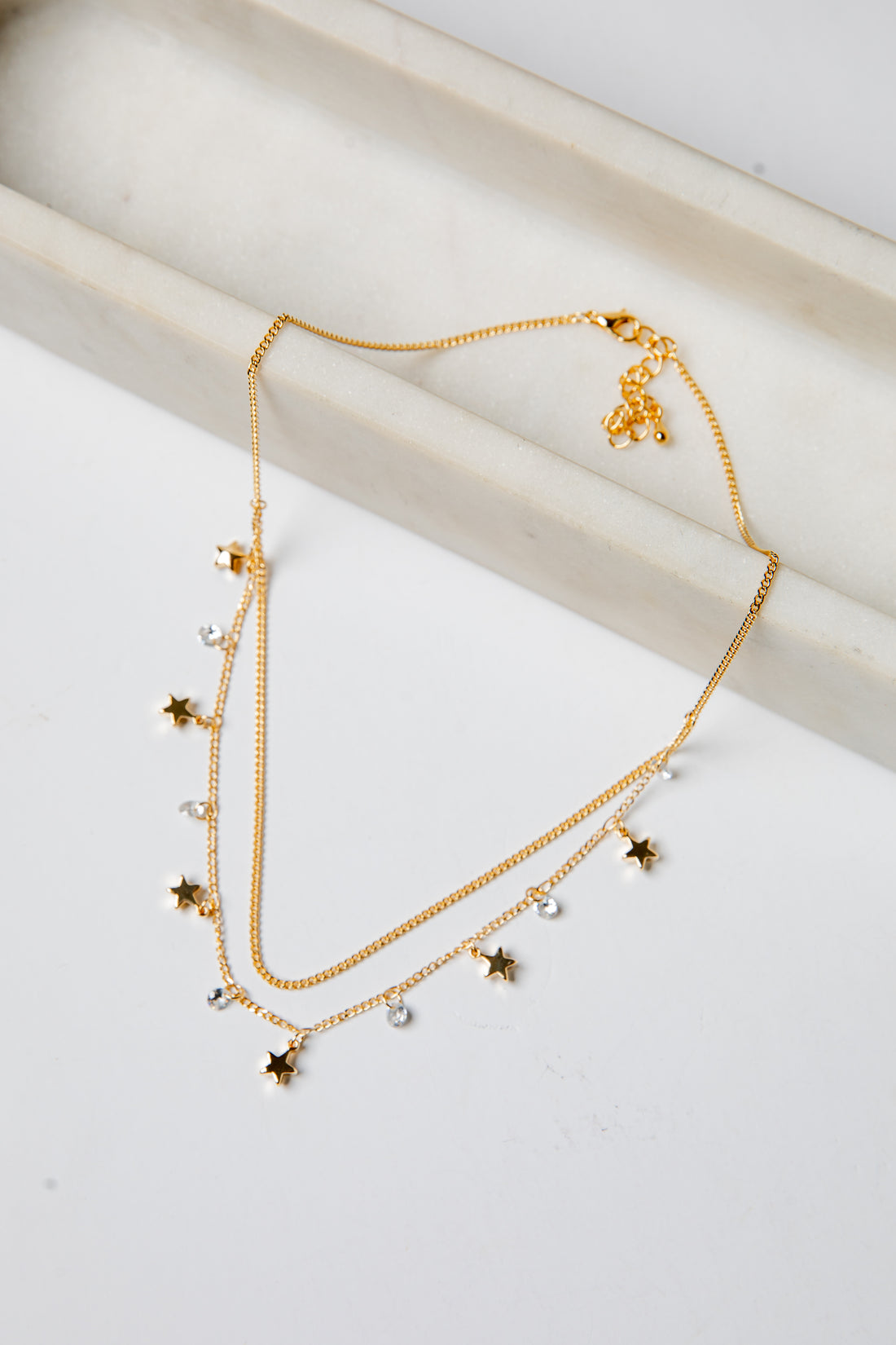 Gold necklace with star-shaped charms on a light background