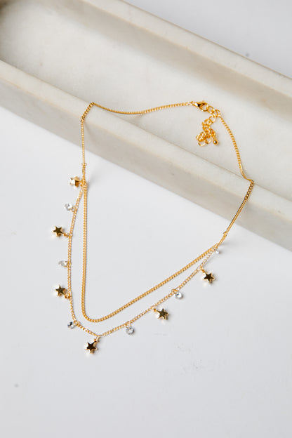 Gold necklace with star-shaped charms on a light background