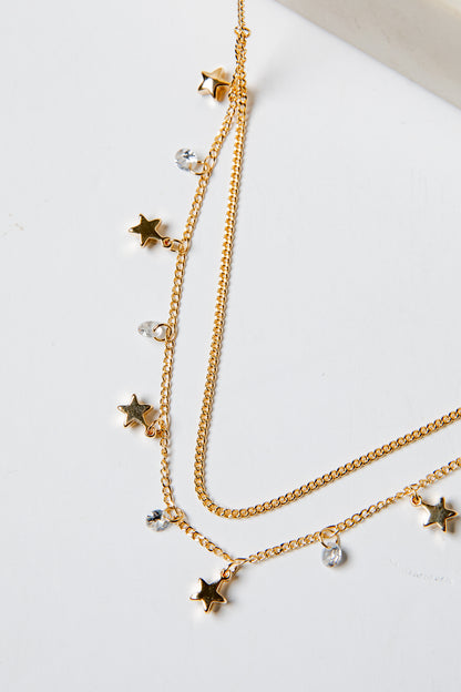 Gold necklaces with star and gemstone pendants on a light background