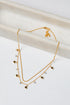 Gold layered necklace with star and heart pendants on a light background