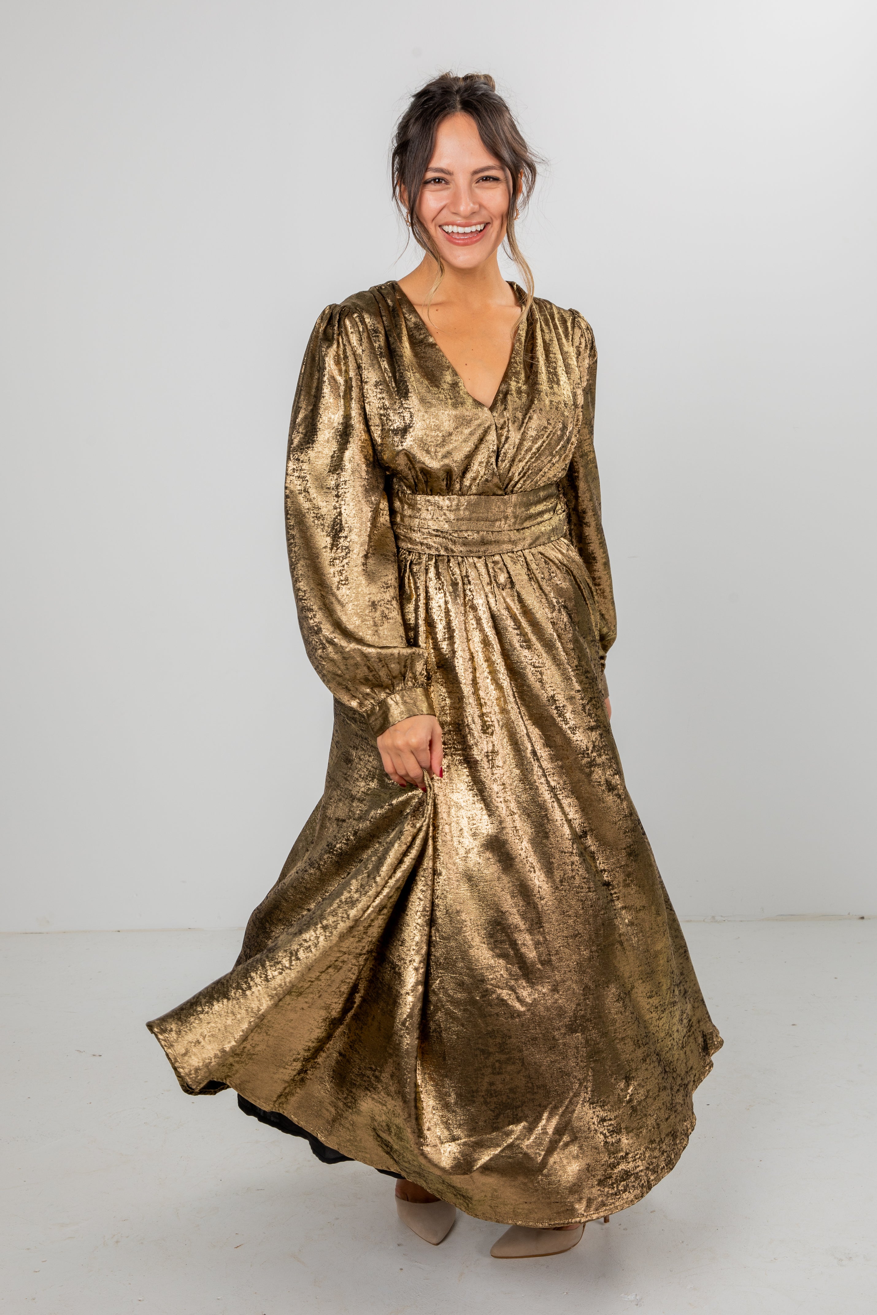 Woman wearing a gold metallic dress on a white background