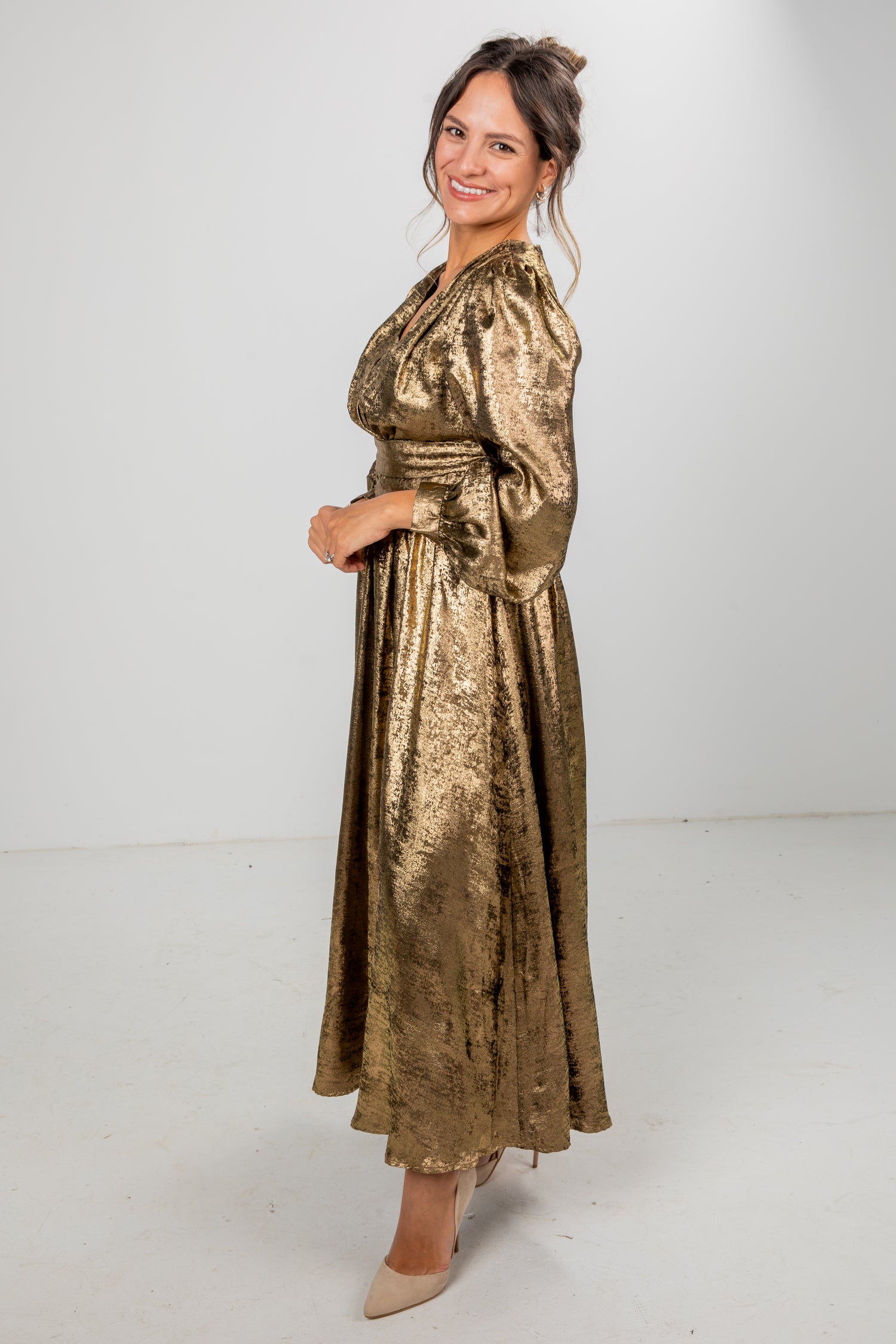 Woman wearing a gold metallic dress against a white background