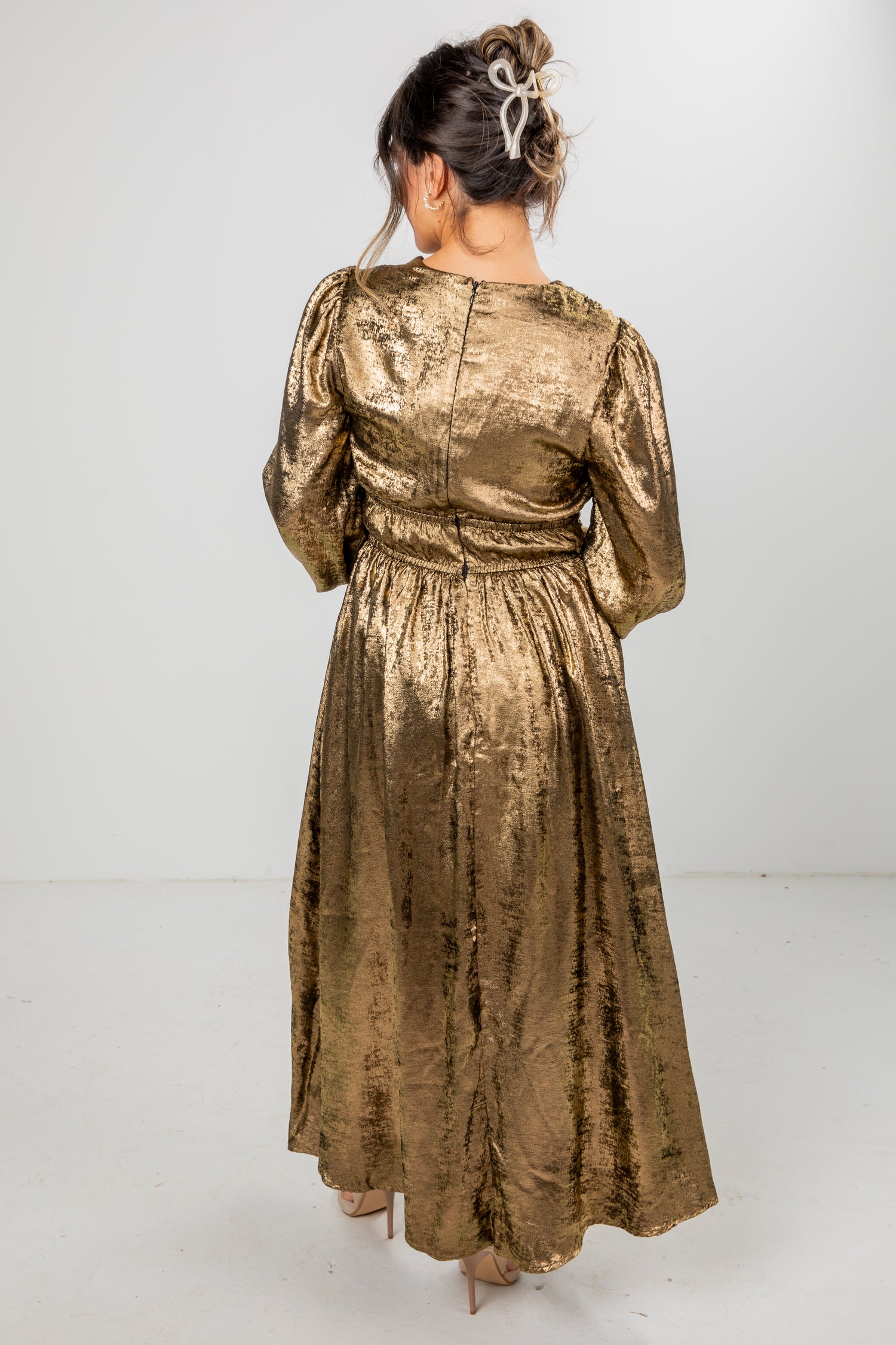 Woman wearing a gold metallic dress against a white background