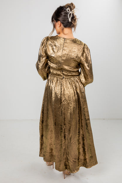 Woman wearing a gold metallic dress against a white background