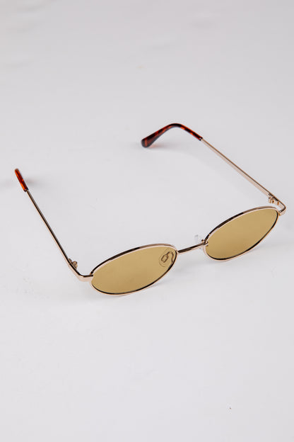 Gold-framed sunglasses with oval lenses on a white background