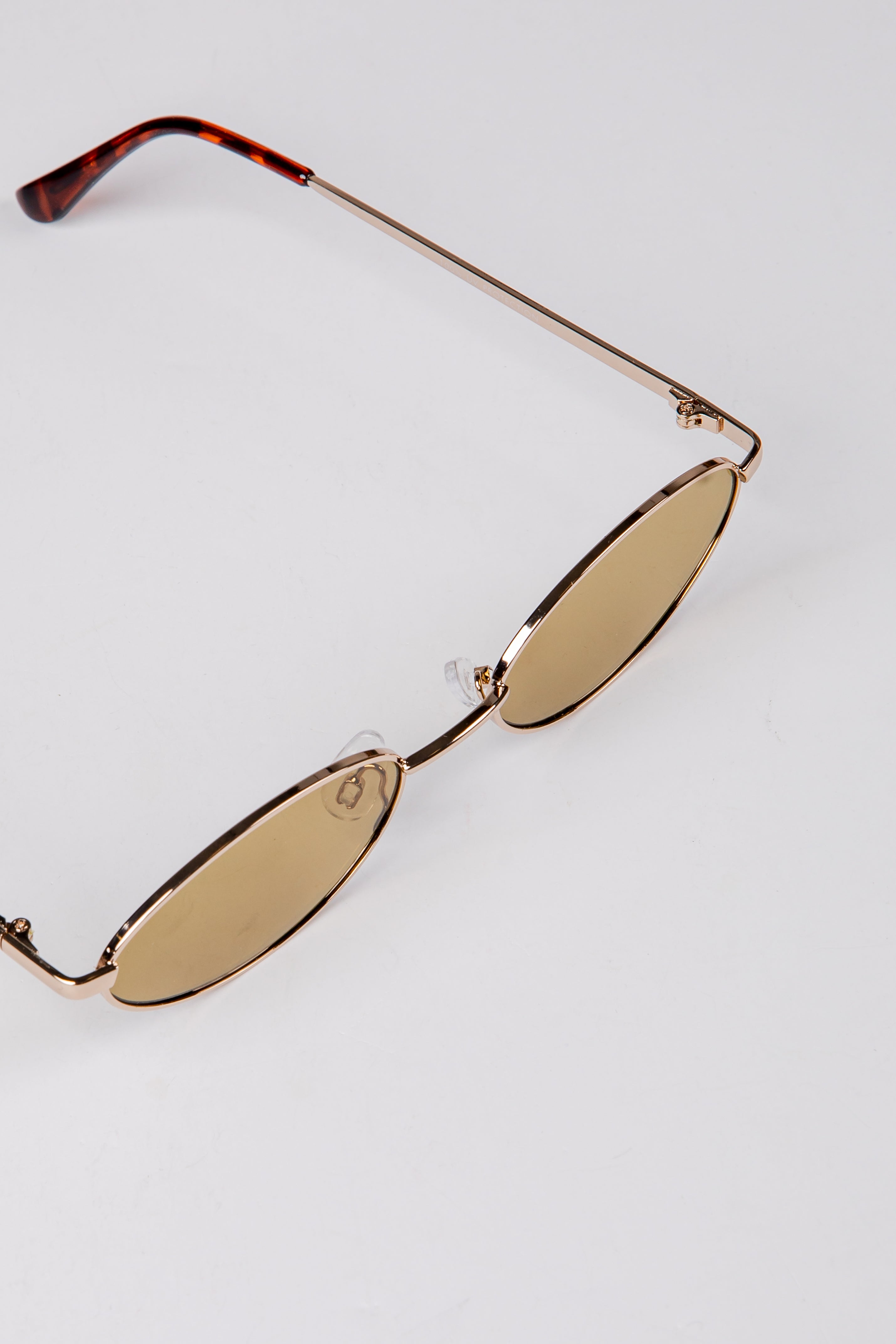 Gold sunglasses with tortoiseshell arms on a light gray background