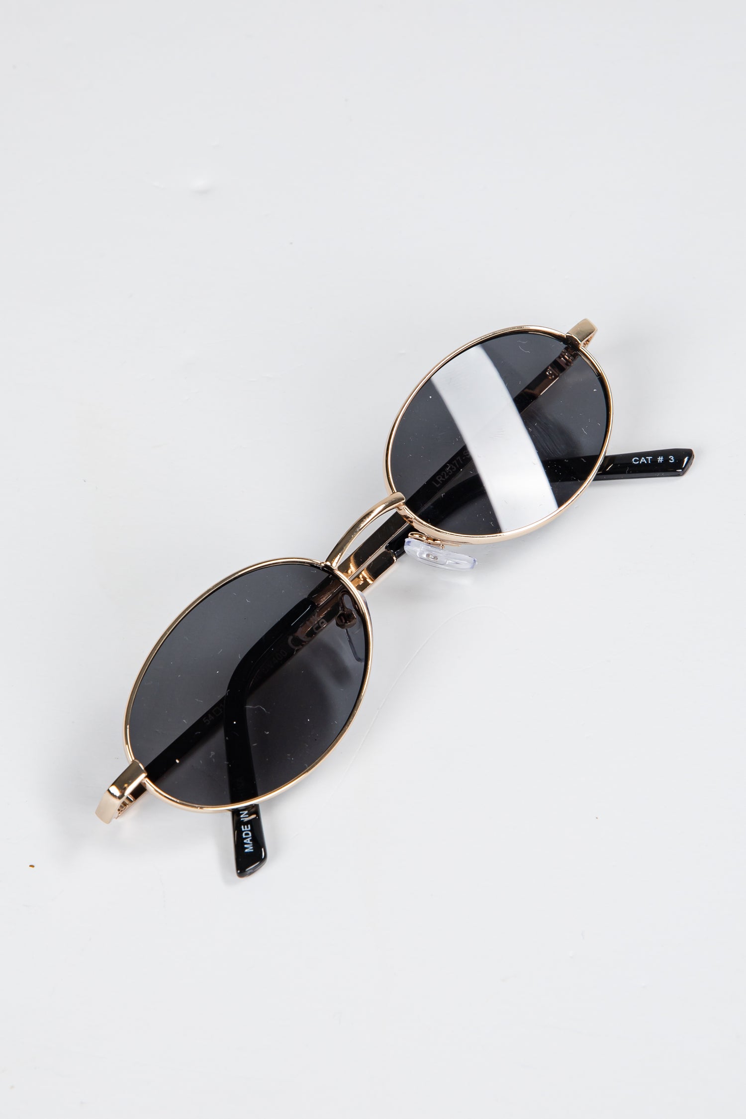 Sunglasses with gold frames and black lenses on a white background