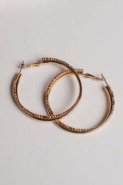 A pair of gold-tone hoop earrings with a textured, beaded outer edge and solid inner bands, displayed on a clean white background.