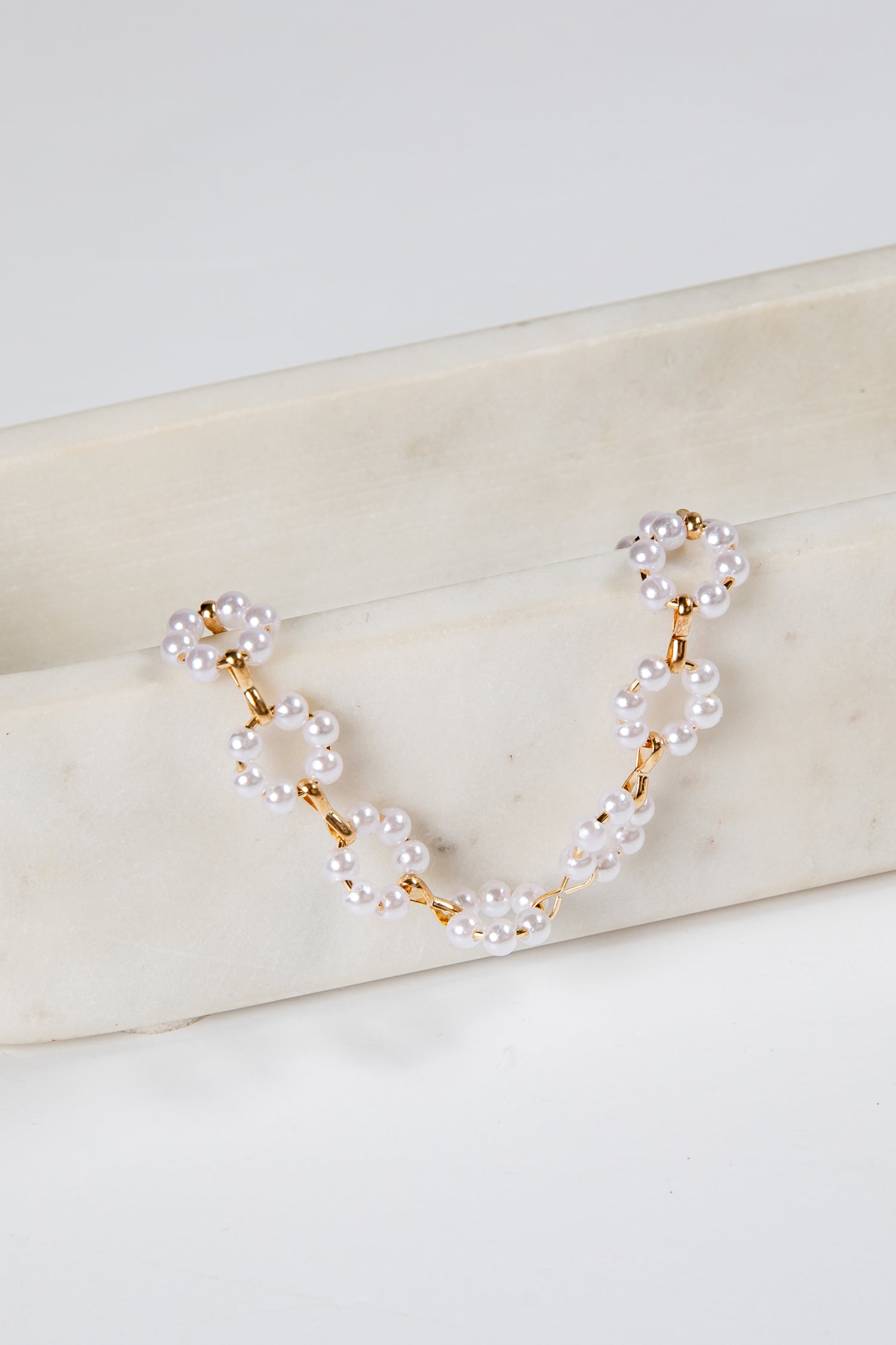 Pearl and gold chain necklace on a marble surface