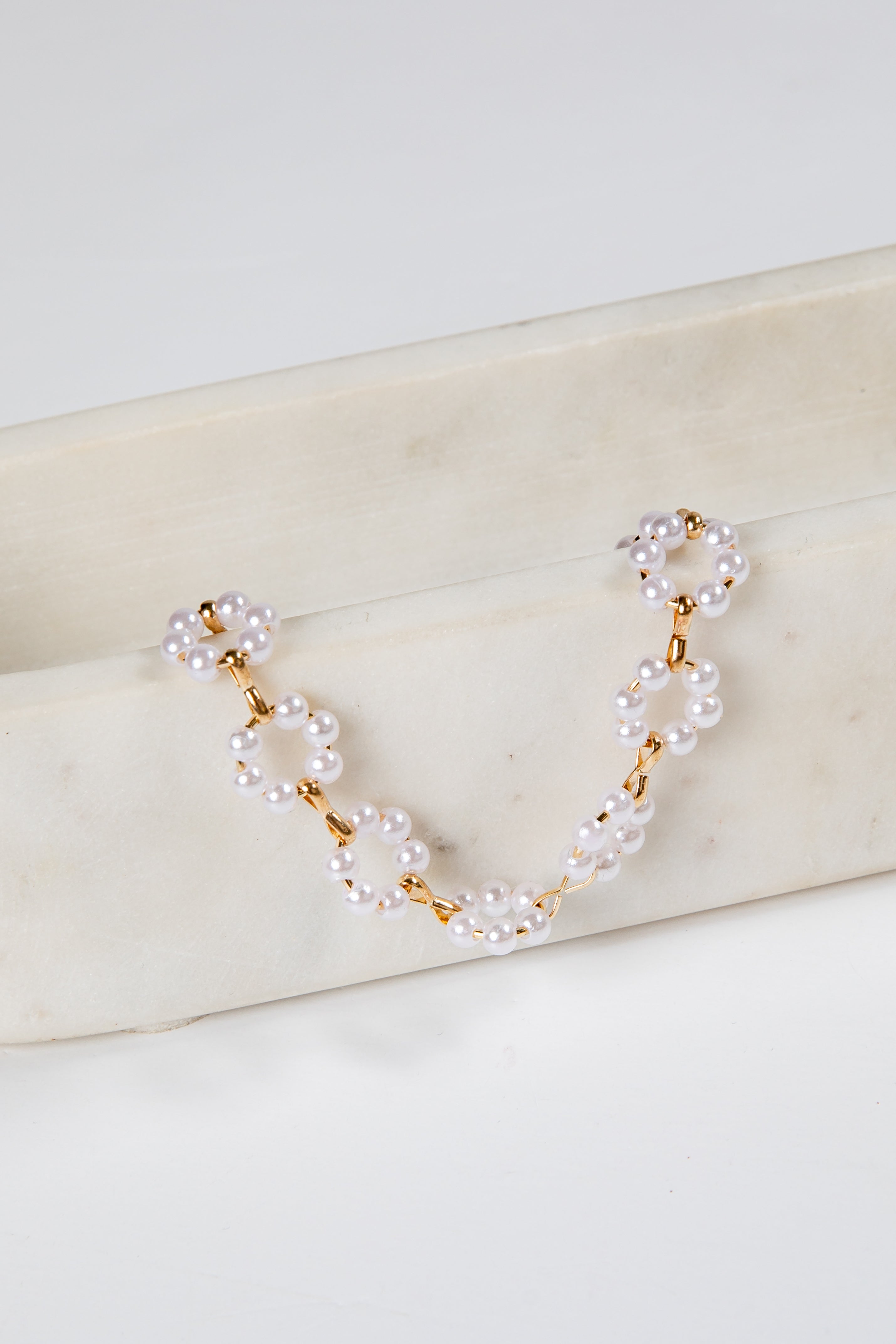 Pearl and gold chain necklace on a marble surface