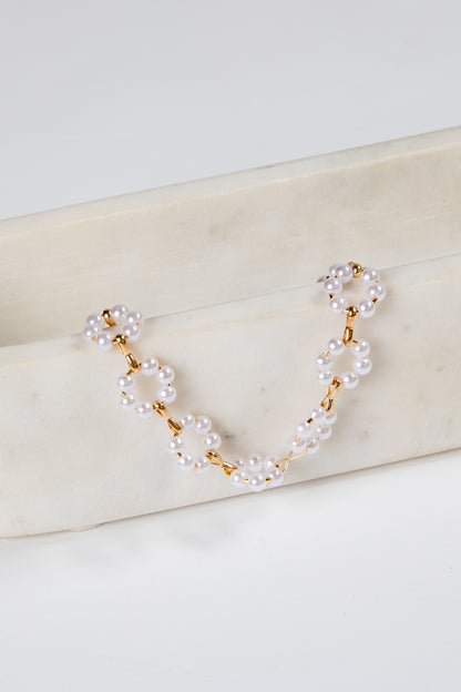 Pearl and gold chain necklace on a marble surface