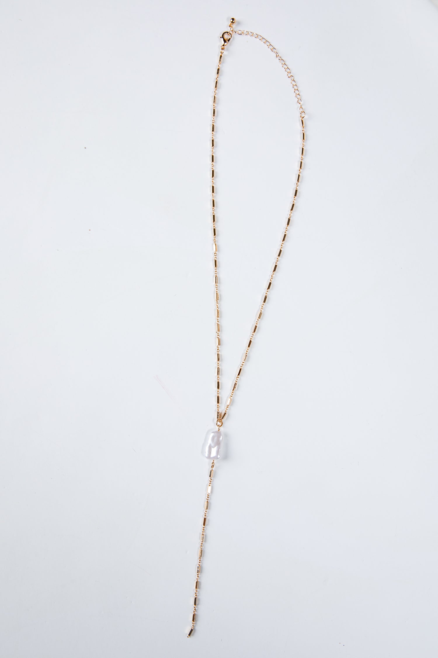 Long necklace with a clear pendant on a light gray background