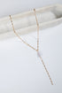 Delicate gold necklace with a pearl pendant on a white marble surface