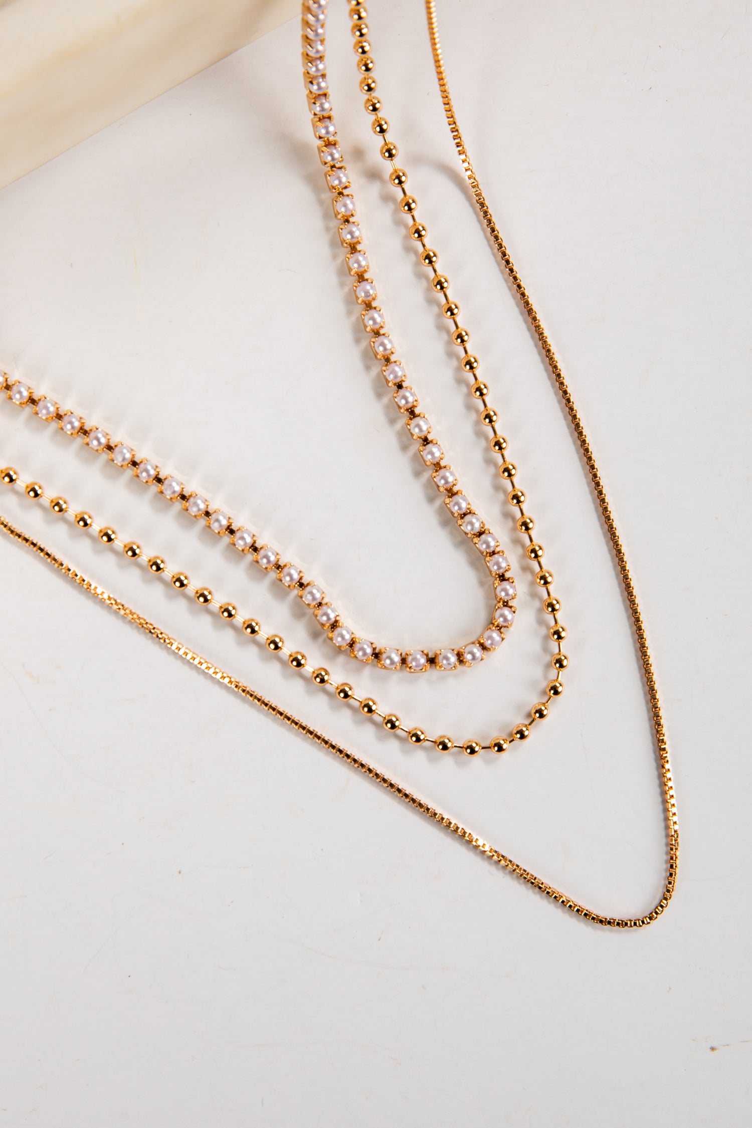 Three gold necklaces on a light background