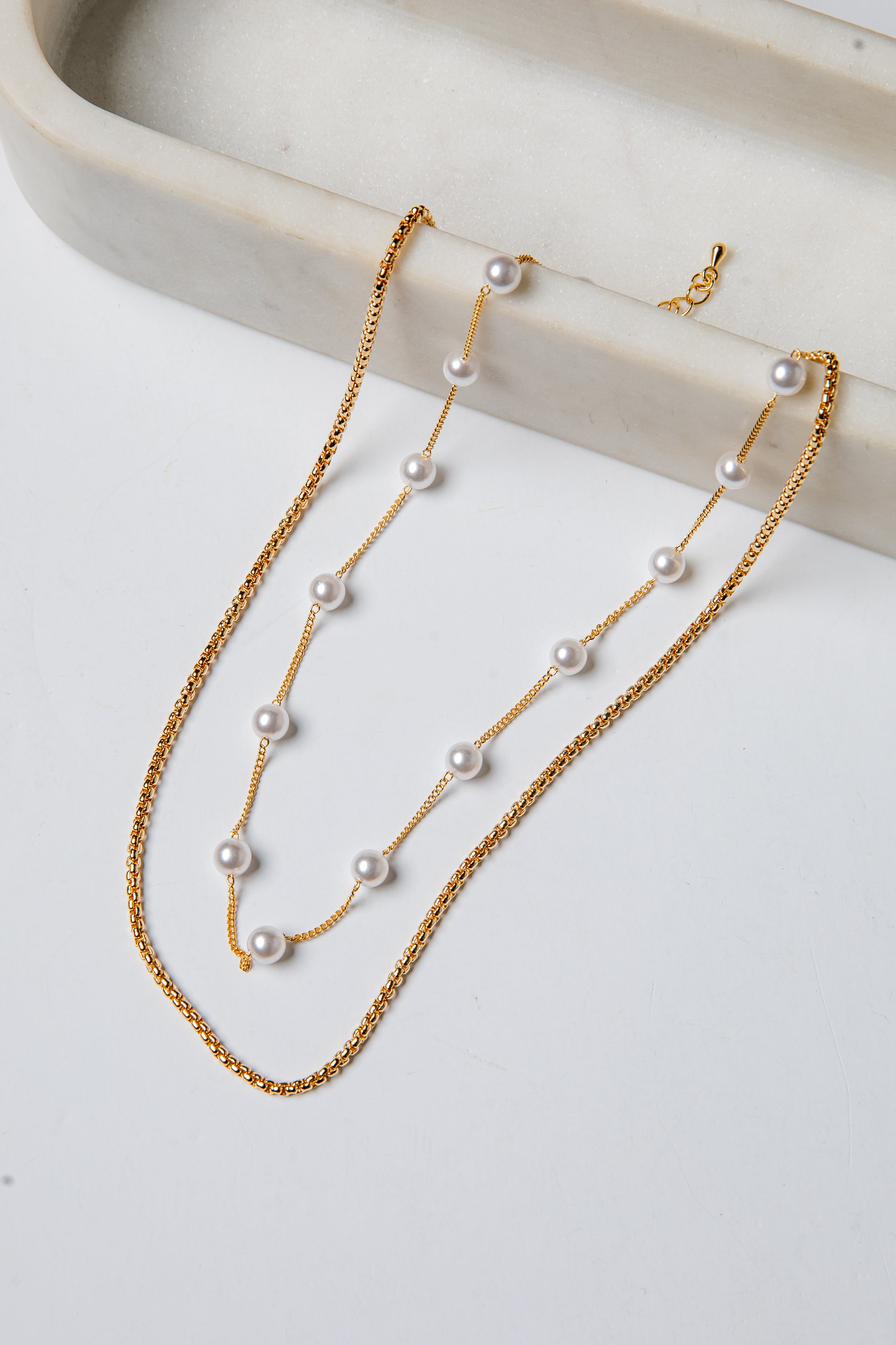 Gold necklace with pearls on a white surface