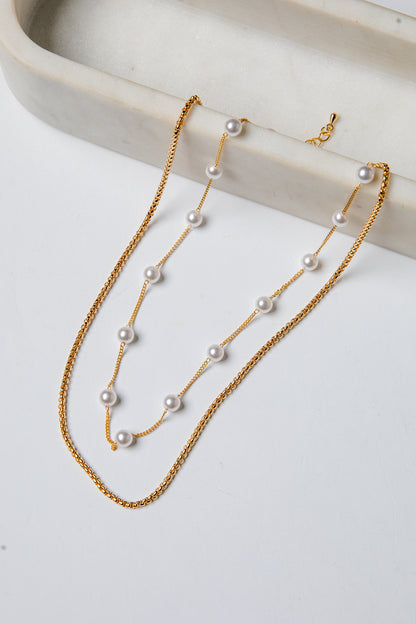 Gold necklace with pearls on a white surface