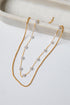 Gold necklace with pearl beads on a white surface