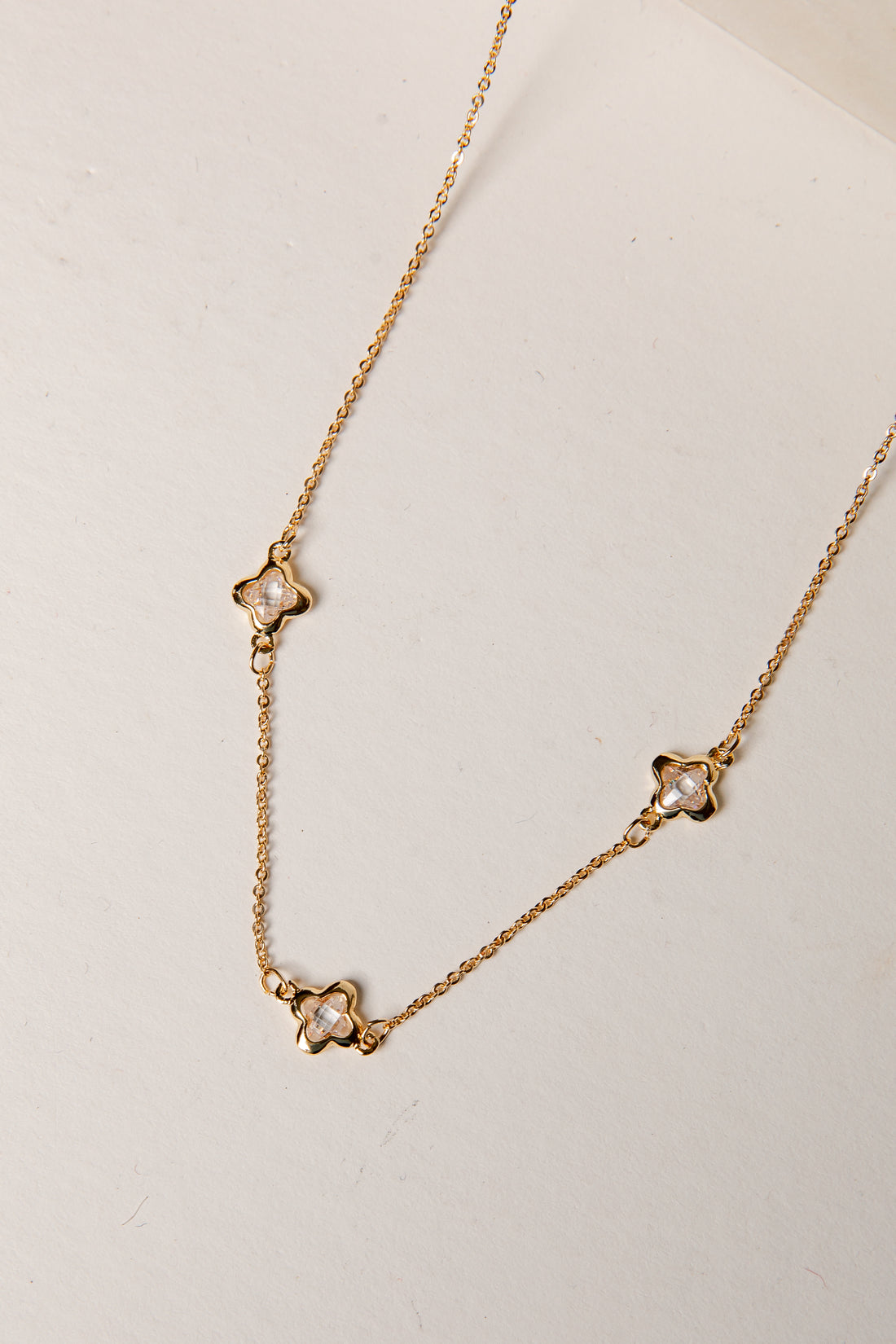 Gold necklace with star-shaped pendants on a light background