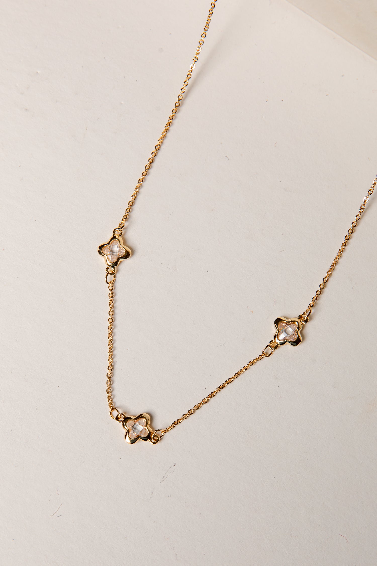 Gold necklace with star-shaped pendants on a light background