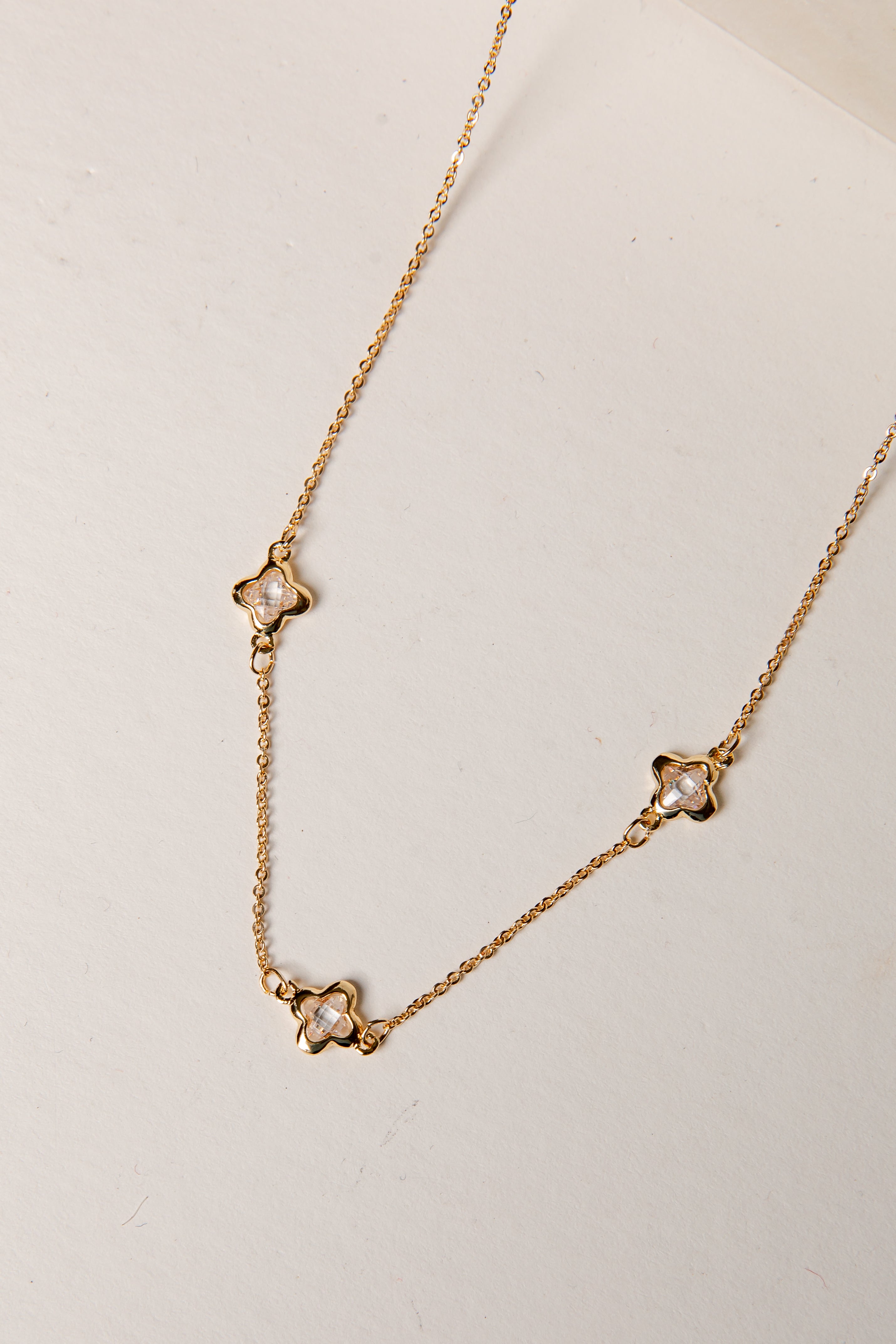 Gold necklace with star-shaped pendants on a light background