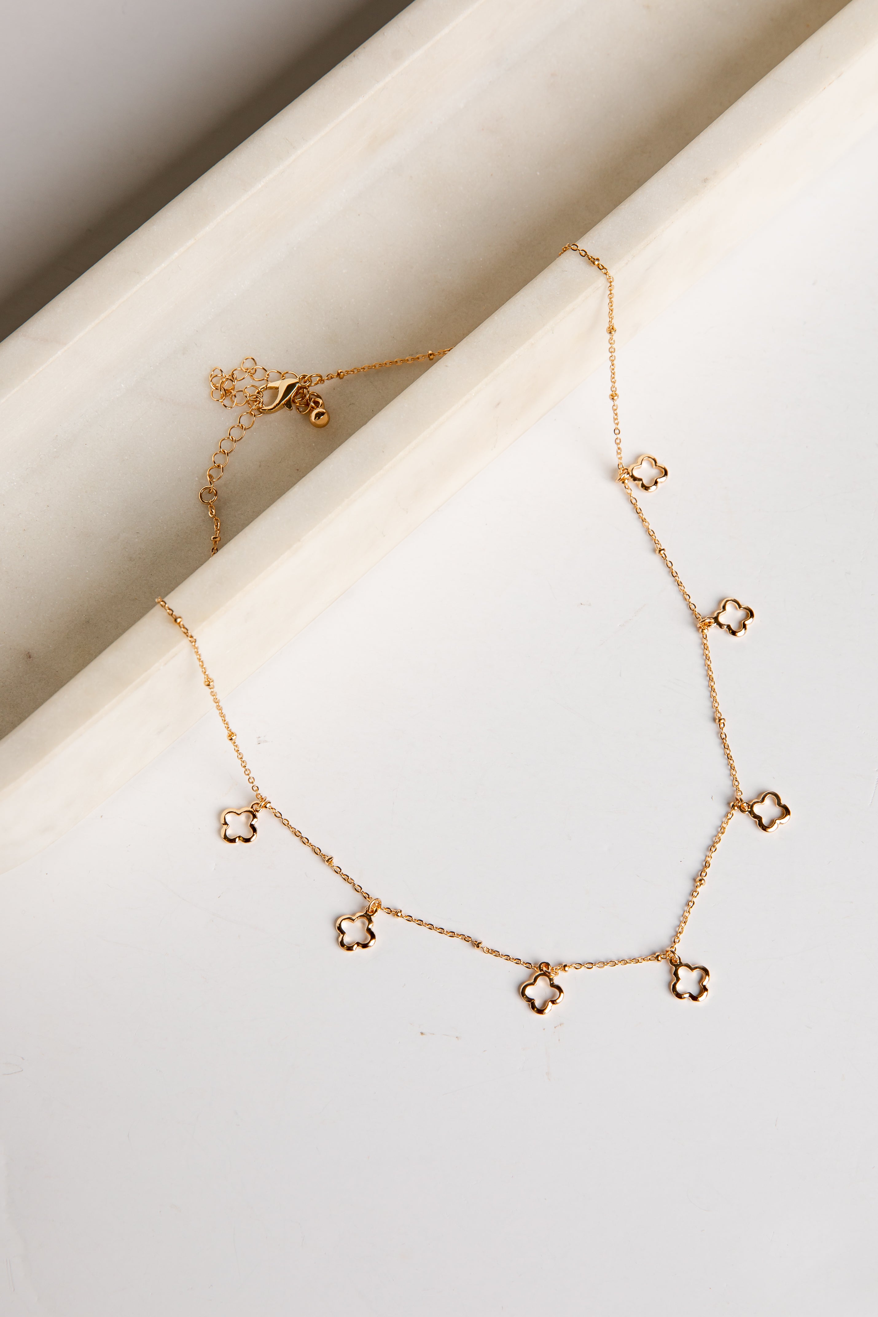 Gold necklace with star-shaped pendants on a white surface