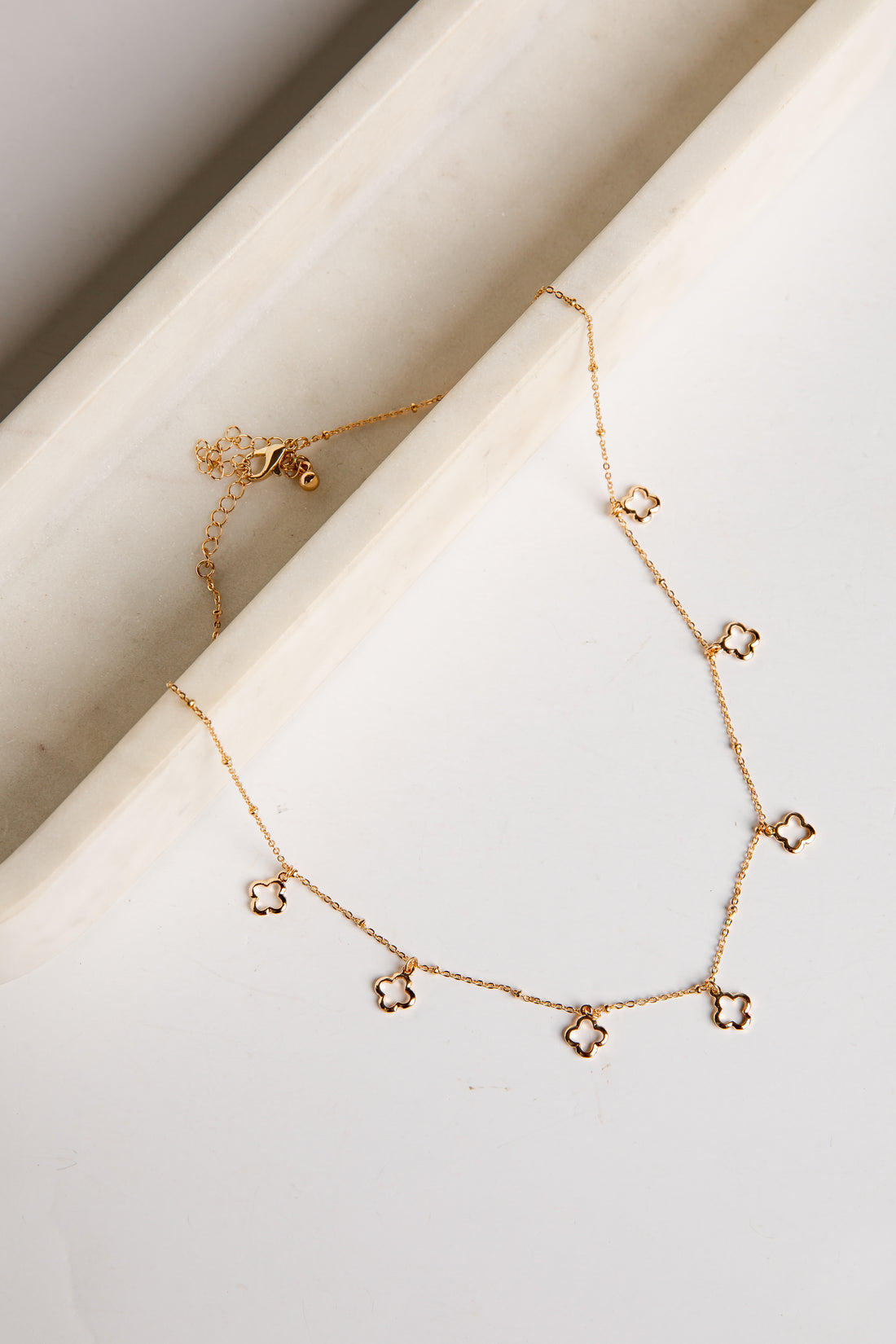 Gold necklace with star-shaped pendants on a light background